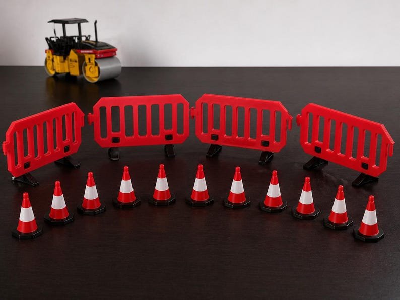 Miniature UK Traffic Cones & Roadwork Barriers Set May include: A set of miniature construction site equipment including four red plastic interlocking safety barriers and twelve small orange and white traffic cones, with a yellow and black toy road roller positioned in the background.