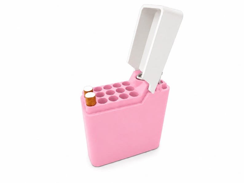 Pink Cigarette Case with Lighter Holder — King Size, 15 Cigarettes May include: A light pink cigarette case with a white hinged lid. The case features a grid of cylindrical slots for individual cigarettes, with two cigarettes visible in the front left slots. The exterior is smooth and solid in colour.