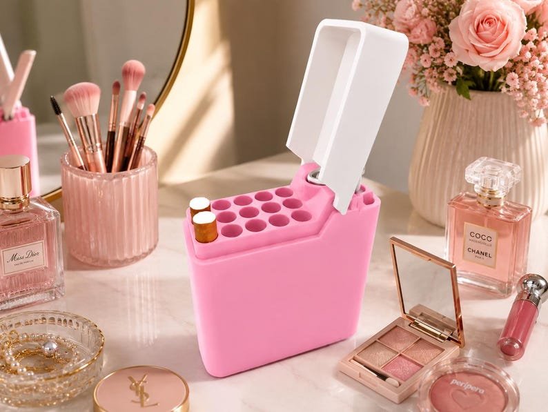 Pink Cigarette Case with Lighter Holder — King Size, 15 Cigarettes May include: A bright pink silicone makeup organiser featuring multiple circular slots for lipsticks and a hinged white lid. The rectangular container has a stepped design with a taller back section and a shorter front section, providing storage for various cosmetic items.