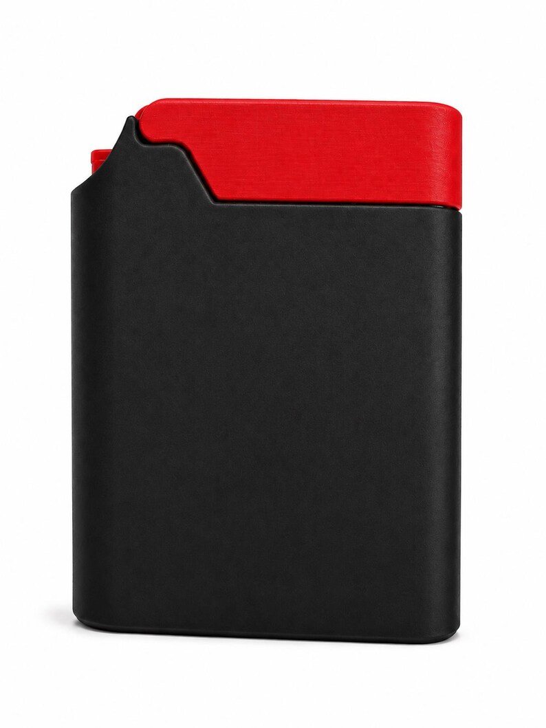 Packout Inspired Cigarette Case (King size / cigarette 8) May include: A rectangular, matte black case with a vibrant red top section. The case features a distinct, notched cutout on the upper left side, revealing a small portion of the red interior mechanism. The design is sleek, flat, and minimalist.