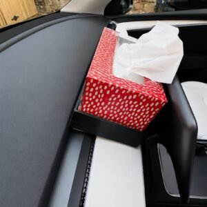 May include: A rectangular tissue box holder with a vibrant red exterior featuring a white polka dot pattern. The holder is mounted on the dashboard of a vehicle and contains a stack of white facial tissues protruding from the top opening.