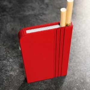 May include: A bright red rectangular cigarette case with vertical grooved detailing on the side. The case features a top opening that holds two cigarettes with tan filters exposed, and a small white button visible on the left side of the frame.