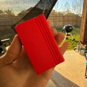 May include: A rectangular, bright red object with a smooth, matte finish and three parallel vertical grooves running along one side. The item has a flat, solid construction with clean, sharp edges and a uniform, vibrant red colour throughout its surface.